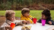 Des enfants déjeunent dehors.