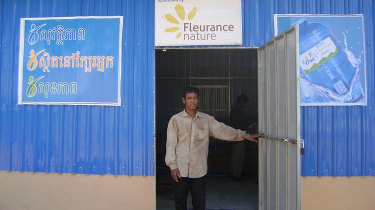 Un homme sort d'une station de production d'eau potable de 1001Fontaines sponsorisée par Fleurance Nature.