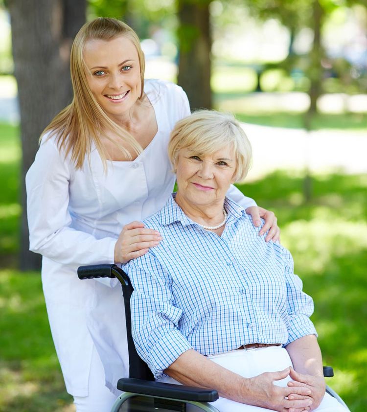 Photo d'une soignante promenant une dame en fauteuil
