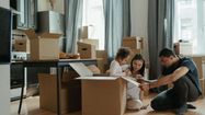 Une famille écrit sur des cartons de déménagement installés dans leur cuisine.