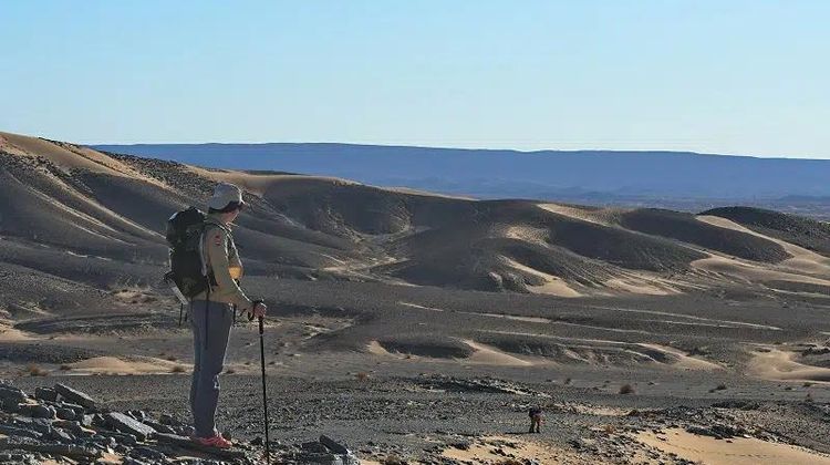 Une participante du Trek'In Gazelles sur le haut d'une dune dans le désert.