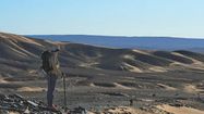Une participante du Trek'In Gazelles sur le haut d'une dune dans le désert.