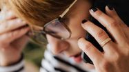 Une femme tient sa tête d'une main pendant qu'elle téléphone.