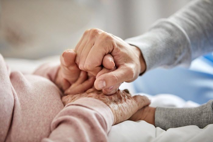 Une personne âgée tient les mains d'une personne plus jeune.