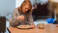 Une femme, seule devant une assiette de pâte.