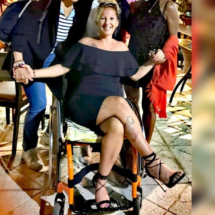 Sylvie Charlet en robe et talon haut, assise sur son fauteuil.