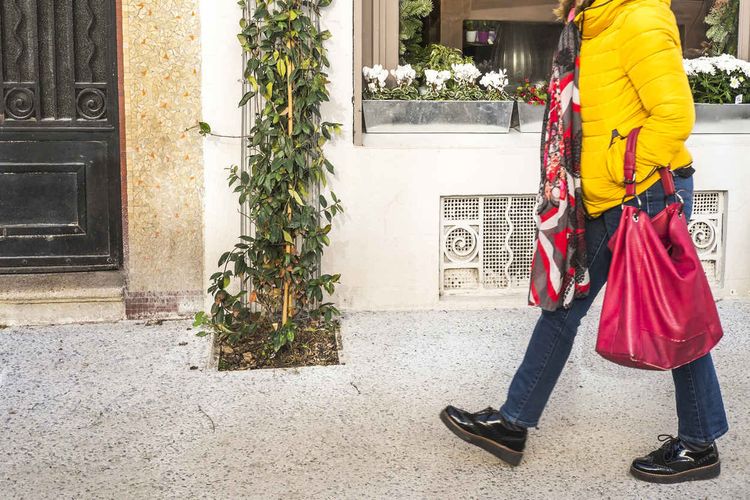 Une femme marche sur le trottoir et passe devant une plante grimpante, plantée grâce au permis de jardiner développé par la Maison du jardinier et de la nature en ville, à Pau