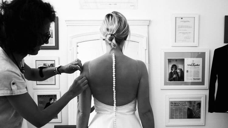 Claire Abdelkader dans son atelier de Dax, retouche une robe de mariée sur une femme.