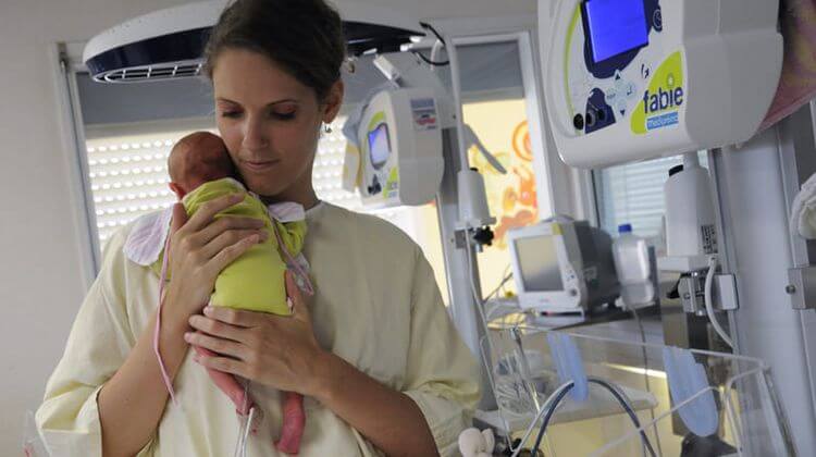 Une femme tient un bébé dans ses bras dans un hôpital.