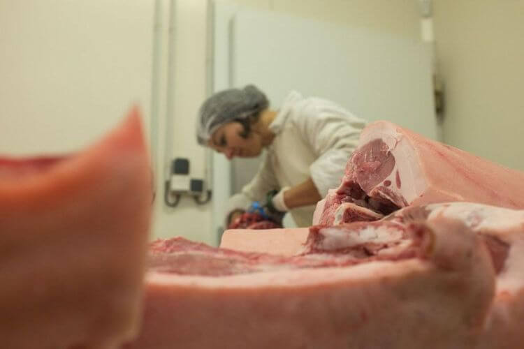 Noémie en tenue de travail en train de découper la viande dans un atelier