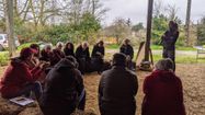 Des personnes rassemblées autour d'un paysan en train de discuter de la situation des agriculteurs assis sur des bottes de foin