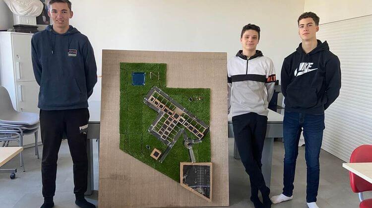 Les trois adolescents posent à côté du plan du futur écoquartier.