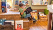 Un petit garçon dans l'espace jeunesse de la librairie en train de lire un livre avec attention