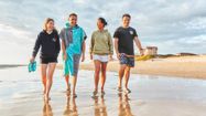 Quatre personnes habillées avec des vêtements Biscaïa marchent le long d'une plage.