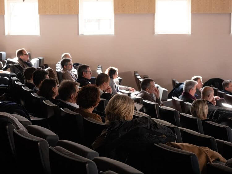 Des personnes assistent à une conférence dans un amphitéâtre.