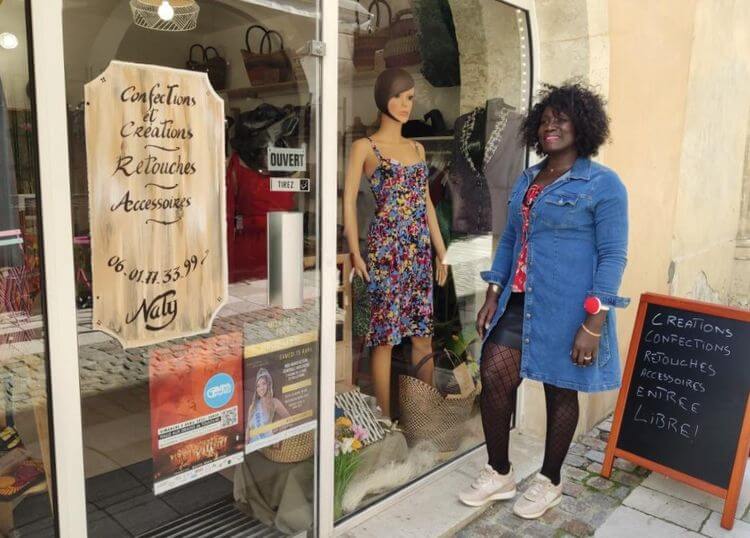 Nathalie Collet devant la devanture de sa boutique à Auch avec des modèles en vitrine