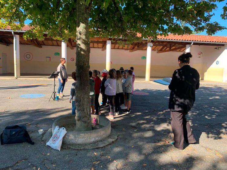 Un groupe d'élèves de Masseube en train de répéter dans la cour de l'école, à l'ombre d'un arbre