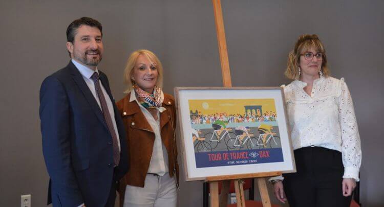 Le Maire de Dax, avec deux femmes, posent devant l'affiche du Tour de France à Dax.