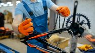 Un ouvrier en train d'installer une chaîne sur un vélo en fabrication