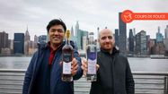 Jeff Diego et David Libespère montrant des bouteilles d'armagnac avec New York en toile de fond