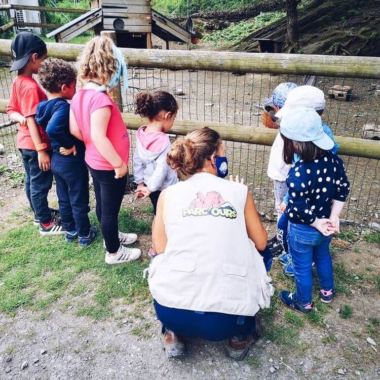Une salariée de Parc'Ours fait visiter le parc animalier à des enfants.