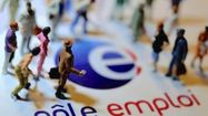 Des figurines sont posées devant un logo du Pôle Emploi.