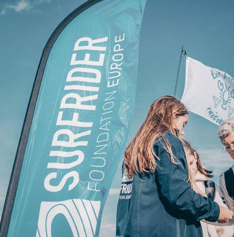Une membre de la Surfrider Foundation devant le drapeau de l'ONG.