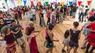 Des festivaliers dansent ensemble toutes générations confondues sous le chapiteau décoré de guirlandes fanions
