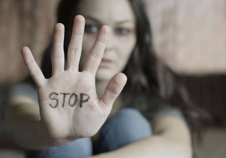 Une femme tend la main avec un stop écrit dans sa pomme.