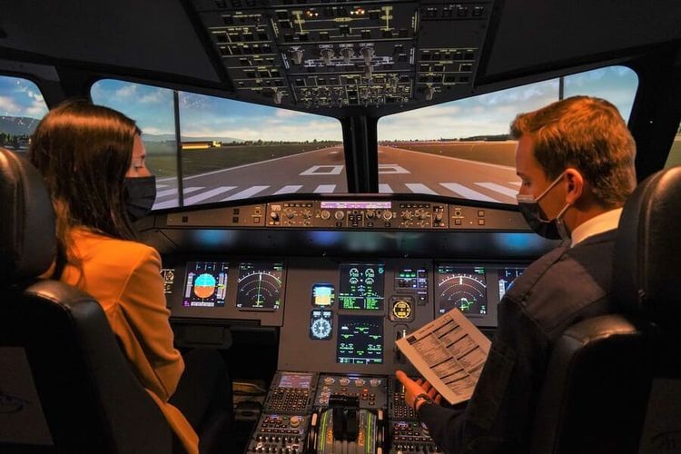 Un instructeur expliquant le fonctionnement du simulateur de vol AviaSim à une jeune femme, à Pau.