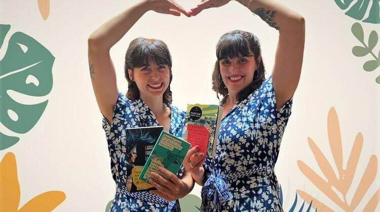 Ariadna et Julie de la librairie La Méridienne tiennent des livres en formant un cœur avec leurs bras