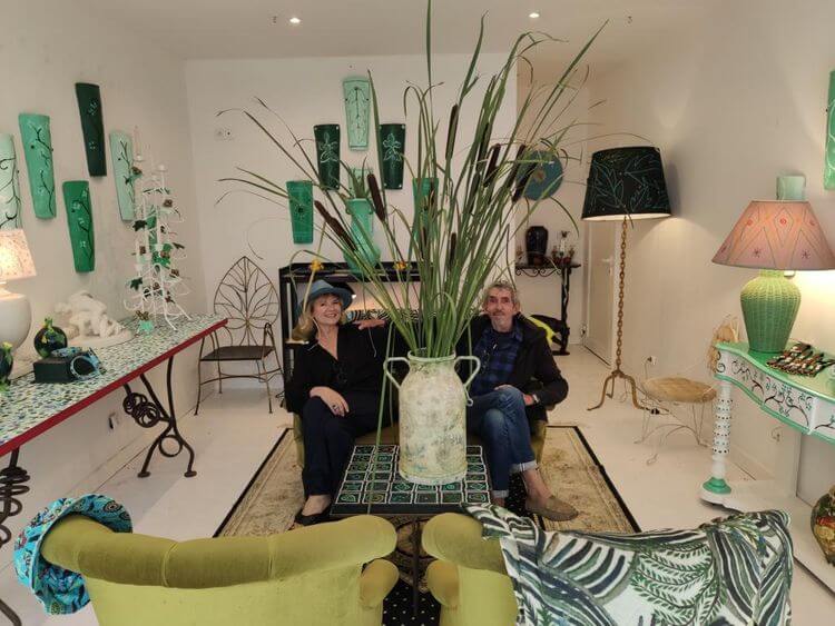 Pascale Bresson Pitras et Michel Klein assis sur un canapé derrière un énorme bouquet de roseaux dans la boutique éphémère