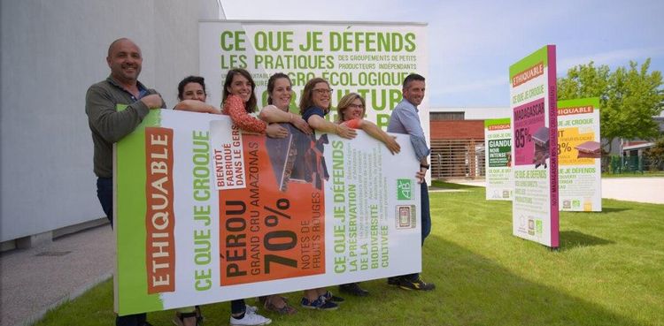 Des employés de la chocolaterie de Fleurance en train de porter une tablette de chocolat géante