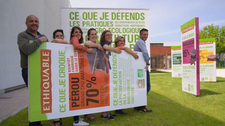 Des employés de la chocolaterie de Fleurance en train de porter une tablette de chocolat géante