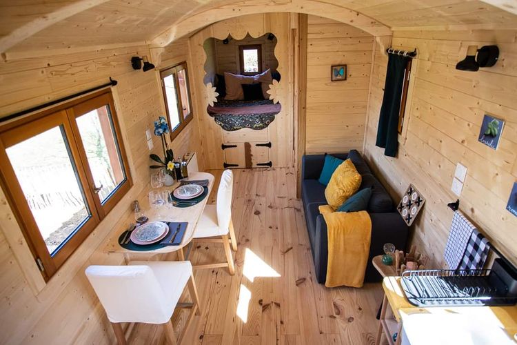 L'intérieur d'une roulotte avec coin repas, petit salon, cuisine et chambre
