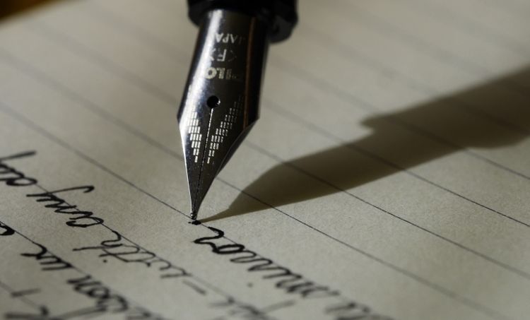 Un stylo à plume écrivant sur une feuille.