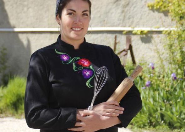 Nadège Blasig tenant dans ses mains un rouleau et un fouet à pâtisserie dans une cour extérieure