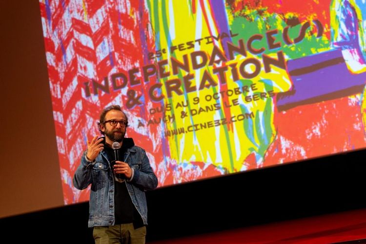 Un réalisateur venu présenter son film au public devant l'écran indiquant le 25e festival