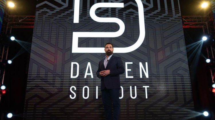 Damien Soitout sur une scène avec le logo de son groupe en arrière plan