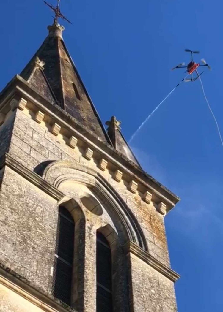 Un drone en train de propulser le produit nettoyant sur la toiture d'une église
