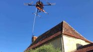 Un drone équipé d'une lance en train de survoler la toiture d'une maison
