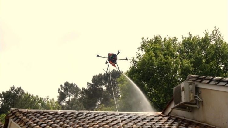 Un drone propulsant le liquide nettoyant sur la toiture d'une maison à l'aide d'une lance