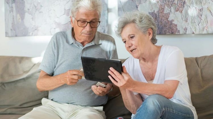 Deux séniors regardent une tablette.