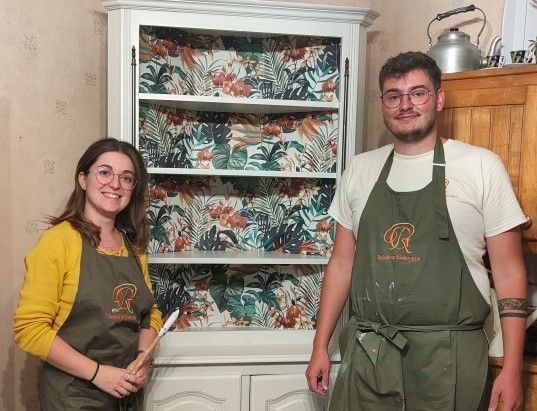 Alexandra et Raphaël Lalanne en tablier de peinture posent devant un vaisselier rénové