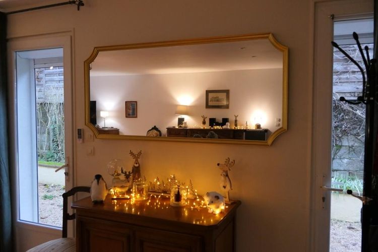 Un grand miroir installé dans le séjour, un meuble décoré avec de petits luminaires, des animaux en bois, etc.