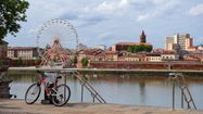 Un vélo sur les berges de la Garonne avec vue sur Toulouse et la grand roue