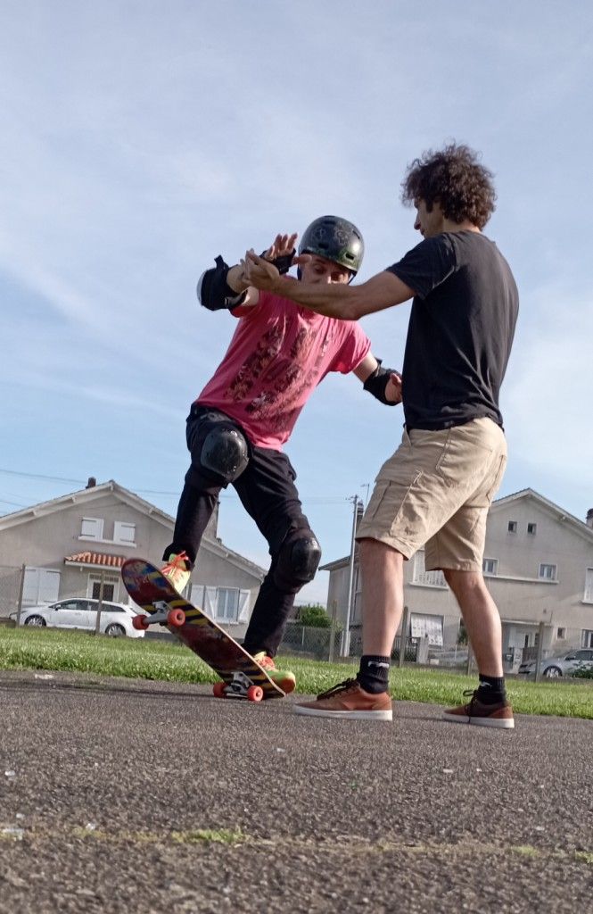 Un homme qui s'initie au skate avec Cyril Paillas qui l'accompagne