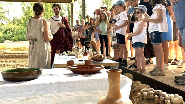 Des enfants assistent à la présentation du quotidien romain à la Domus Cieutat avec deux adultes vêtus de toges