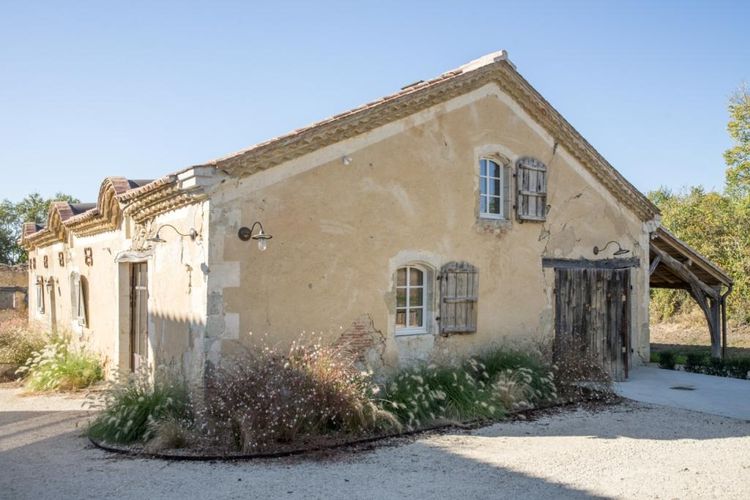 Une vieille bâtisse gasconne avec des fleurs servant de chai pour l'élevage des vinaigres