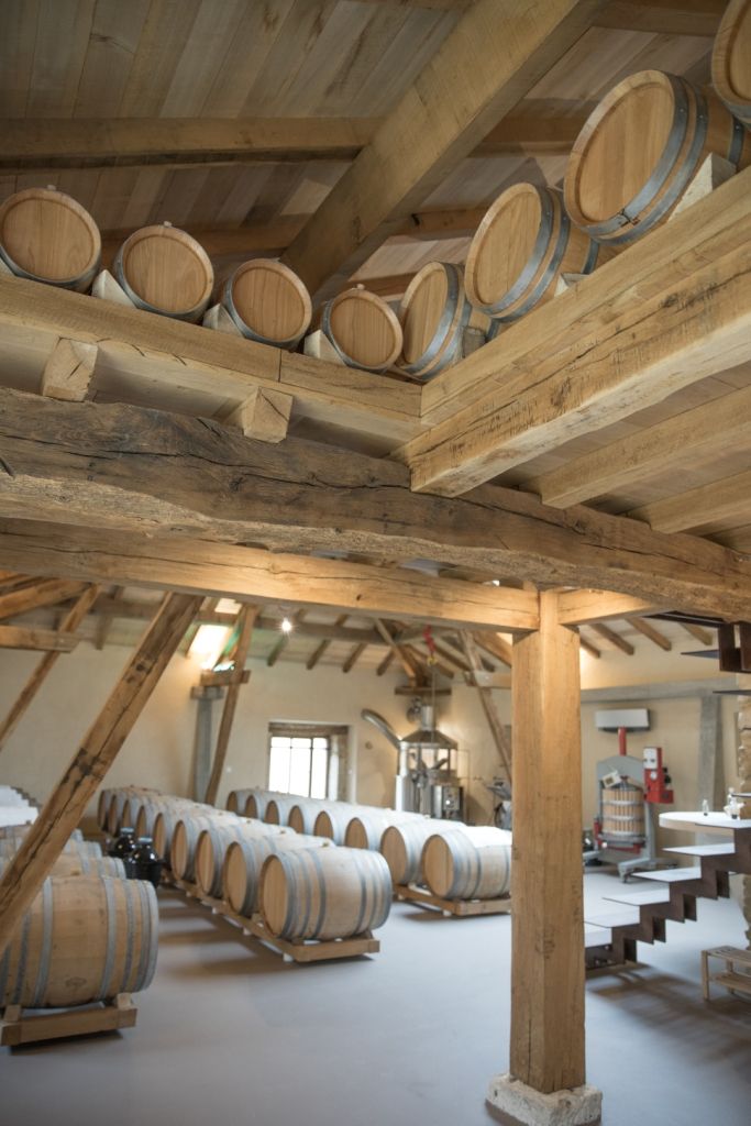 L'intérieur d'un chai du Domaine de l'Airial avec de nombreuses barriques en chêne soigneusement alignées